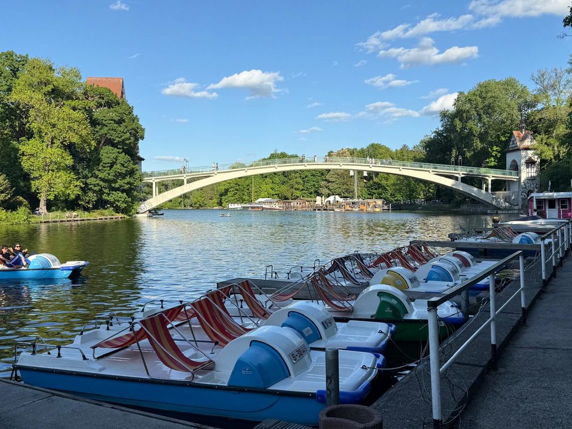Tretboote mit roten Sonnenliegen am Bootssteg der Spree in Berlin, im Hintergrund die Abteibrücke und ein fahrendes Boot